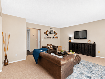 Jacksonville apartment for rent - A living room with a brown couch and a flat screen TV mounted on the wall.
