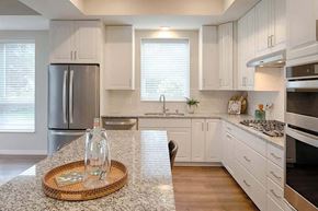 Edina apartment for rent - a kitchen with white cabinets and a table with a vase on it