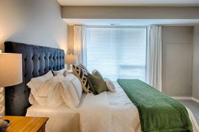 Shakopee apartment for rent - a bedroom with a large bed with white sheets and a green blanket on top of it