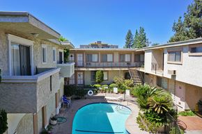 Northridge apartment for rent - A swimming pool is surrounded by a patio with chairs and a table.