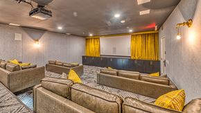 Los Angeles apartment for rent - A room with a row of brown couches and a black bed with yellow curtains.