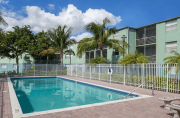 Miami apartment for rent - A pool surrounded by a fence and trees.