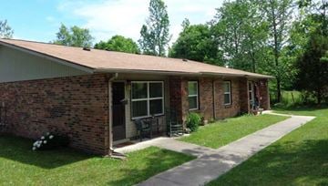 Westmoreland apartment for rent - A small brick house with a porch and a green lawn.
