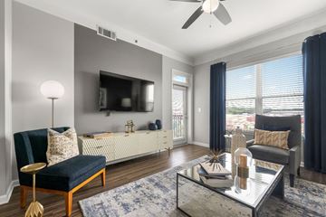 Atlanta apartment for rent - A living room with a blue rug and a glass coffee table.