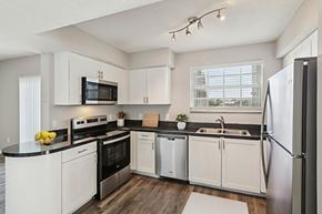 Oakland Park apartment for rent - A modern kitchen with white cabinets and stainless steel appliances.