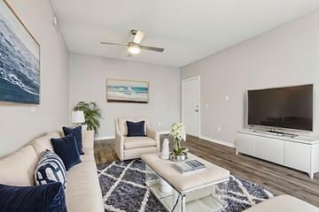 Oakland Park apartment for rent - A living room with a white couch, a coffee table, and a painting on the wall.