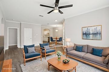 Tampa apartment for rent - A living room with a grey couch, blue chairs, and a painting on the wall.