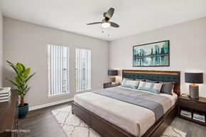 Tampa apartment for rent - A bedroom with a large bed, a ceiling fan, and a painting on the wall.