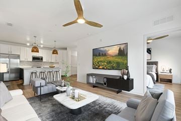 Oviedo apartment for rent - A modern living room with a grey sofa set, a coffee table, a ceiling fan, and a large painting on the wall.