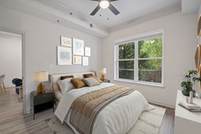 Atlanta apartment for rent - A bedroom with a large bed and a window overlooking a tree-filled yard.
