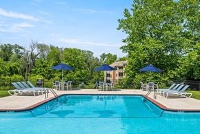 West Chester apartment for rent - A swimming pool surrounded by lawn chairs and umbrellas.