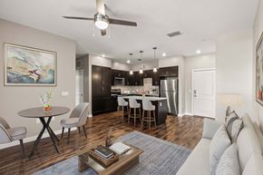 Newberry apartment for rent - Open-plan living room and kitchen with island, dark cabinets and stainless appliances at The Flats at Tioga Town Center.