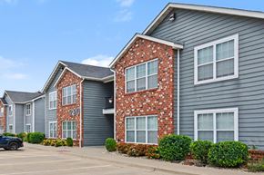 Mascoutah apartment for rent - A black car is parked in front of a grey building with a brick wall.