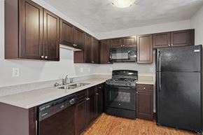 Mascoutah apartment for rent - Northbrooke Commons kitchen with dark colored cabinets, black appliances and granite countertops