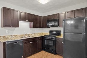 Mascoutah apartment for rent - A kitchen with brown cabinets and black appliances.