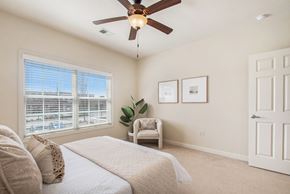Granger apartment for rent - A bedroom with a bed, chair, and pictures on the wall at The Residences at Toscana Park, Granger, IN
