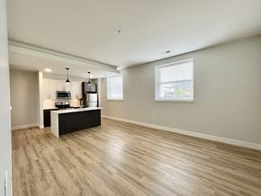 St Louis apartment for rent - A spacious room with light wood flooring and a black and white counter.