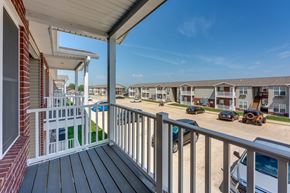 Sedalia apartment for rent - A balcony overlooks a parking lot and apartment buildings.