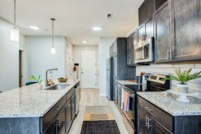 St. Peters apartment for rent - A modern kitchen with dark cabinets and granite countertops.at Bold on the Blvd, Missouri, 63376