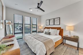 Rogers apartment for rent - Modern bedroom with orange upholstered bed frame at Plaza at Pinnacle Hills Apartments, Rogers, AR