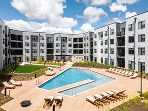 Chesterfield apartment for rent - an apartment building with a pool and lounge chairs at The Flats & Terraces at Wildhorse Village, Missouri
