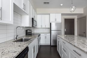 St Louis apartment for rent - Hibernia kitchen with white cabinets, white tile backsplash, granite countertops and stainless steel appliances at Hibernia Apartments, St Louis, MO