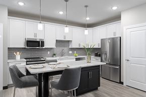 Shiloh apartment for rent - The Oasis at Hartman Lakes kitchen with white cabinetry, light plank flooring, granite countertops, stainless steel appliances, large kitchen island with seating