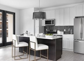 St Louis apartment for rent - Modern kitchen with white cabinet, stainless steel appliances, island with seating and modern light fixture at The Euclid, St Louis, MO, Missouri