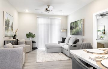 Shiloh apartment for rent - A living room with a grey couch, a white table, and a painting on the wall.