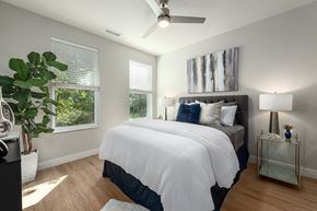 Ellisville apartment for rent - Bedroom with gray upholstered headboard and dual windows at Mila Apartments, Ellisville, Missouri