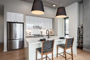 Clayton apartment for rent - Modern kitchen with white island and pendant lighting at Bemiston Place Apartments, Clayton, MO 63105