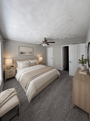 Mascoutah apartment for rent - A bedroom with a large bed, a bench, and a ceiling fan.
