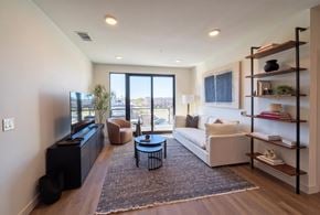 Rogers apartment for rent - A living room with a white couch, a black coffee table, and a large window with a view of the outside.