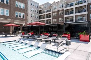 Carmel apartment for rent - A pool area with red umbrellas and lounge chairs.