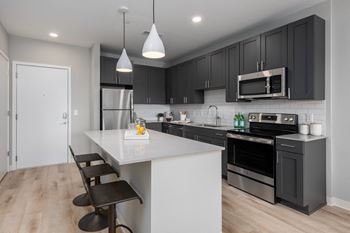 An open kitchen with a white island and black cabinets