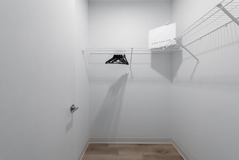 A walk in closet with a white wall and a shoe rack on the wall