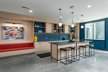 A kitchen with an island and stools in front of a table and a coucha kitchen with an island and stools in front of a table and a couch