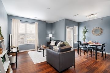 St. Louis apartment for rent - A living room with a grey sofa and a dining table set for six.