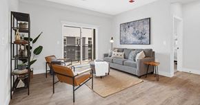 Olivette apartment for rent - A living room with a grey couch, a brown chair, and a brown rug at The Oliver Apartments, Olivette, Missouri