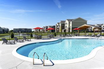 A pool with chairs and umbrellas in front of apartment buildings
