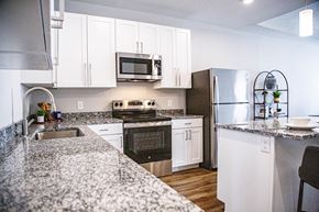 St. Charles apartment for rent - A modern kitchen with granite countertops and stainless steel appliances at French District Villas Apartments, St. Charles