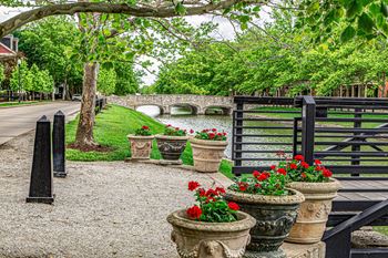 A bridge over a small river with a black gate and a row of flower pots