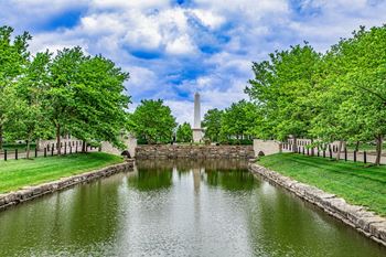 A serene landscape with a water body, trees, and a monument in the background