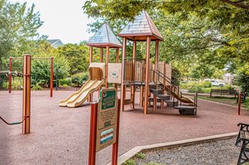 A playground with a yellow slide and a brown wooden structure