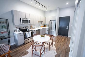 A kitchen with stainless steel appliances and a white table and chairs