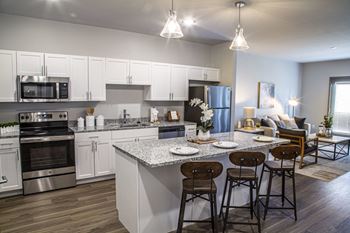 A kitchen and living room with an island and stools