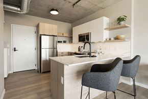 St. Louis apartment for rent - a kitchen with white cabinets and a marble counter top and a stainless steel refrigerator at One Foundry Way, St. Louis, 63110
