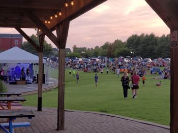 A large gathering of people are sitting on the grass