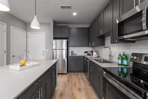 Saint Louis apartment for rent - a kitchen with black cabinets and white counter tops and a stainless steel refrigerator at The Edwin on Grand Apartments, St Louis
