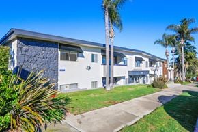 Redondo Beach apartment for rent - A modern building with a stone facade and palm trees in front.